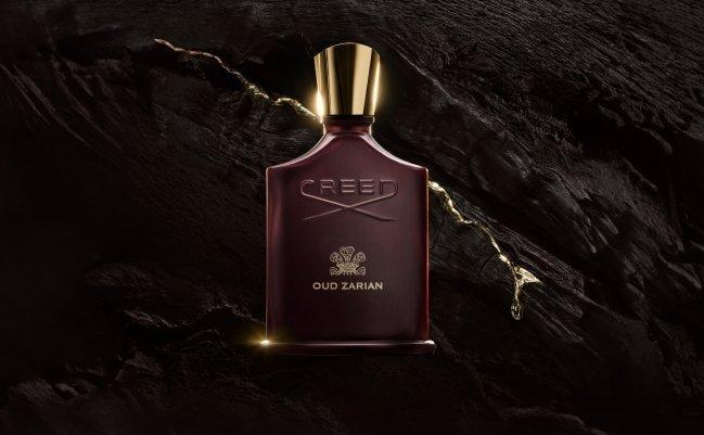A bottle of Creed Aventus cologne displayed on a white platform with dramatic lighting