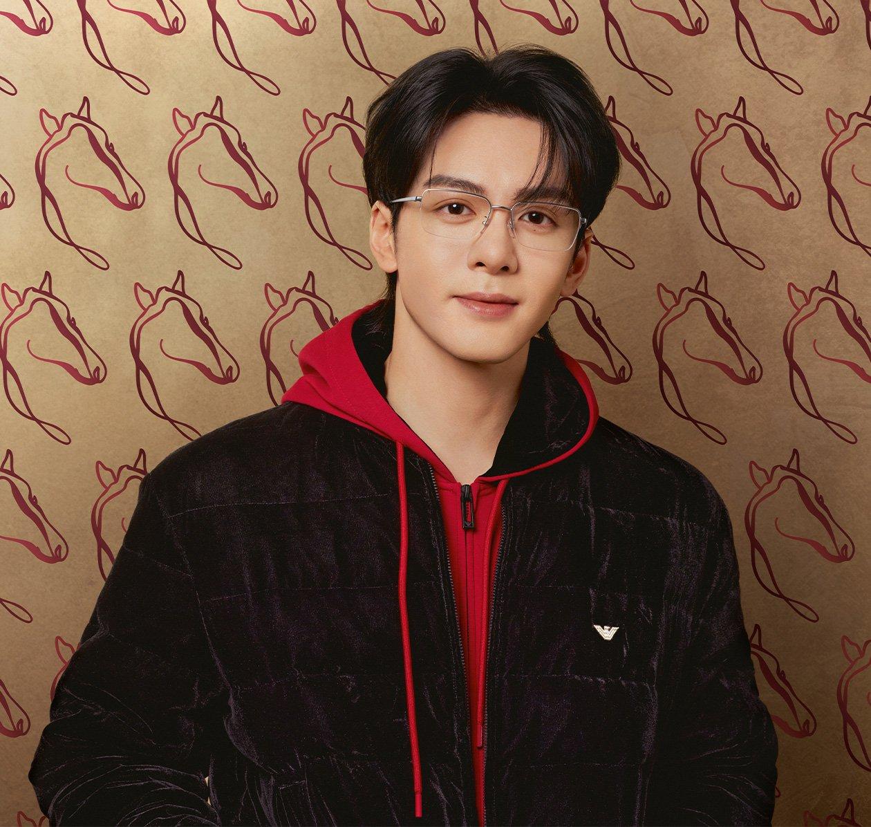 Un homme portant une veste en velours noire d’Emporio Armani avec un hoodie rouge