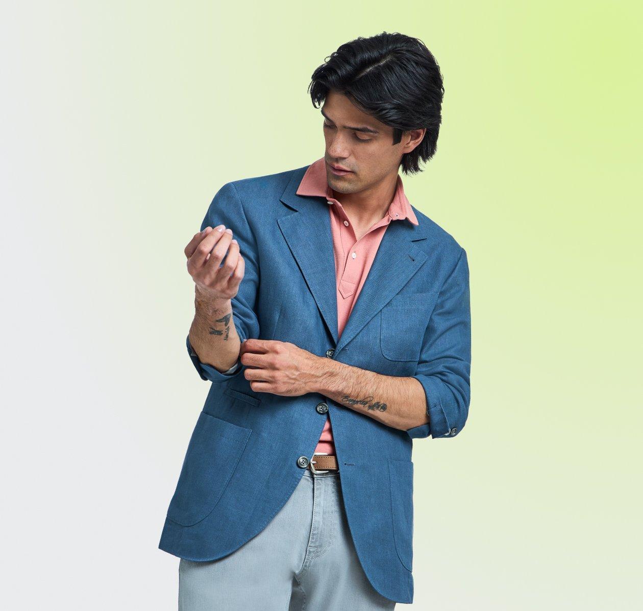 A man wearing a dark blue sport jacket with peach shirt and light blue jeans
