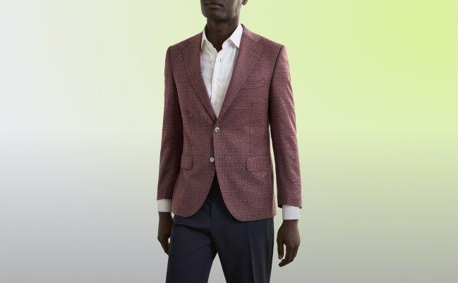 A man wearing a maroon, brown sport jacket with off-white shirt and black pant