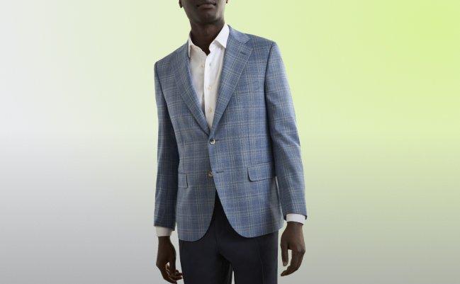 A man wearing a bue-grey sport jacket with off-white shirt and black pant