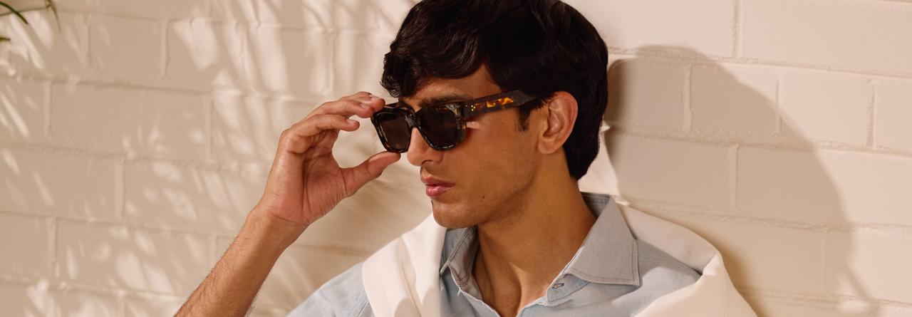  A man wearing a light blue collared shirt with black sunglasses
