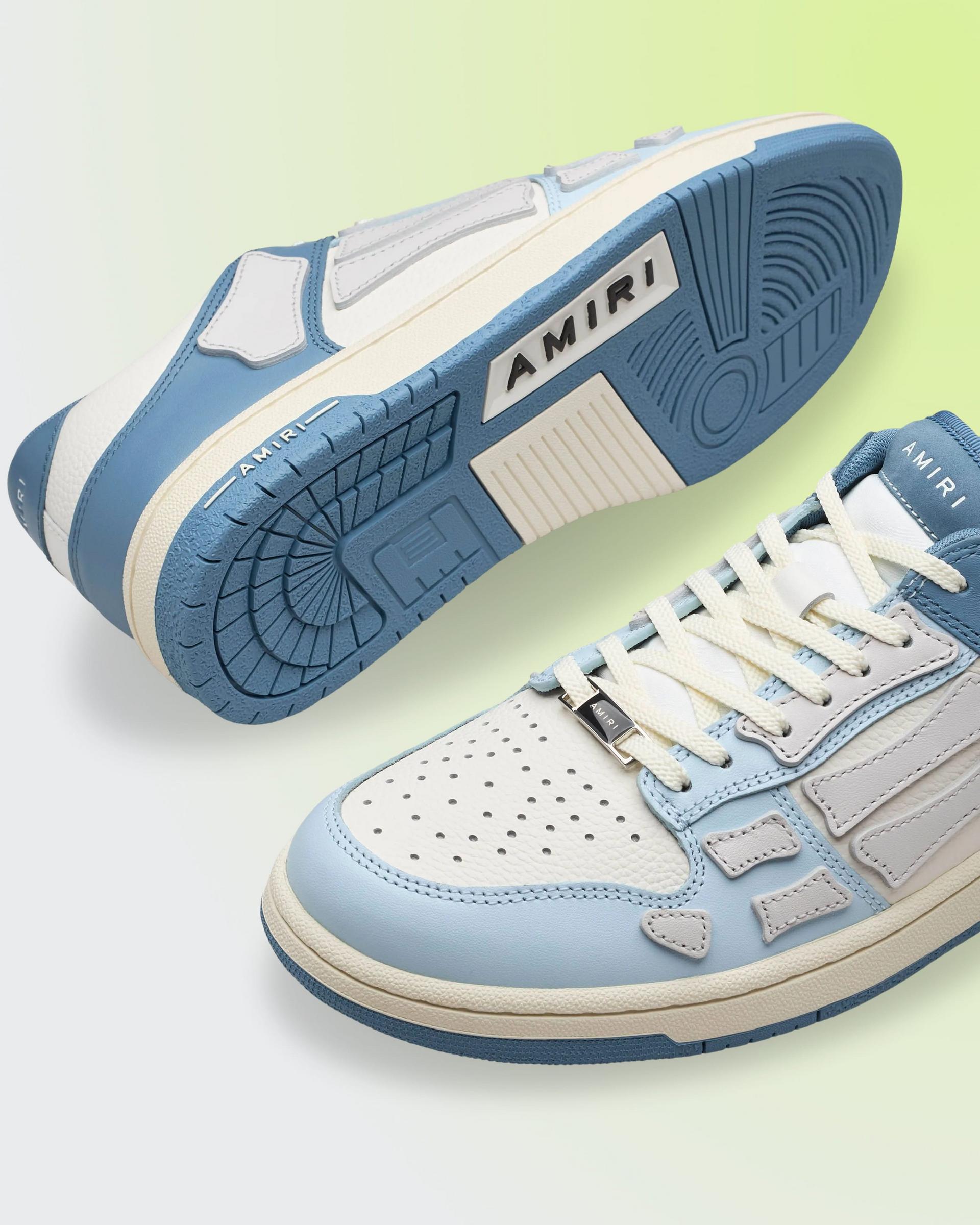 Amiri Sneaker in a blue and white colorway, featuring perforated leather panels, skeletal appliqué detailing, and a two-tone rubber sole