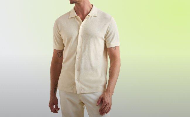 A man wearing a cream-colored short-sleeve button-down knit shirt paired with light-colored trousers