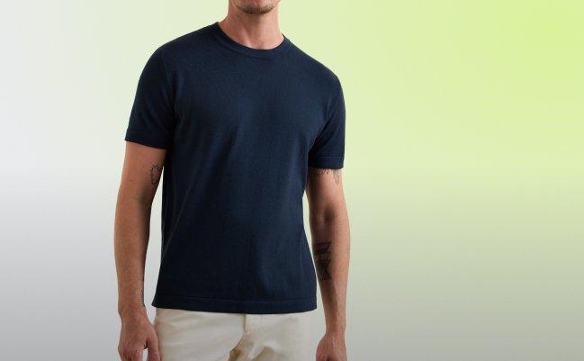 A man wearing a plain navy crew neck T-shirt paired with light-colored trousers