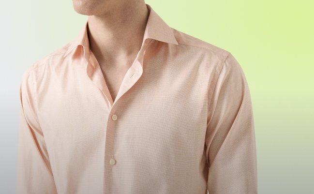A man wearing a light pink color, paired with dark navy trousers