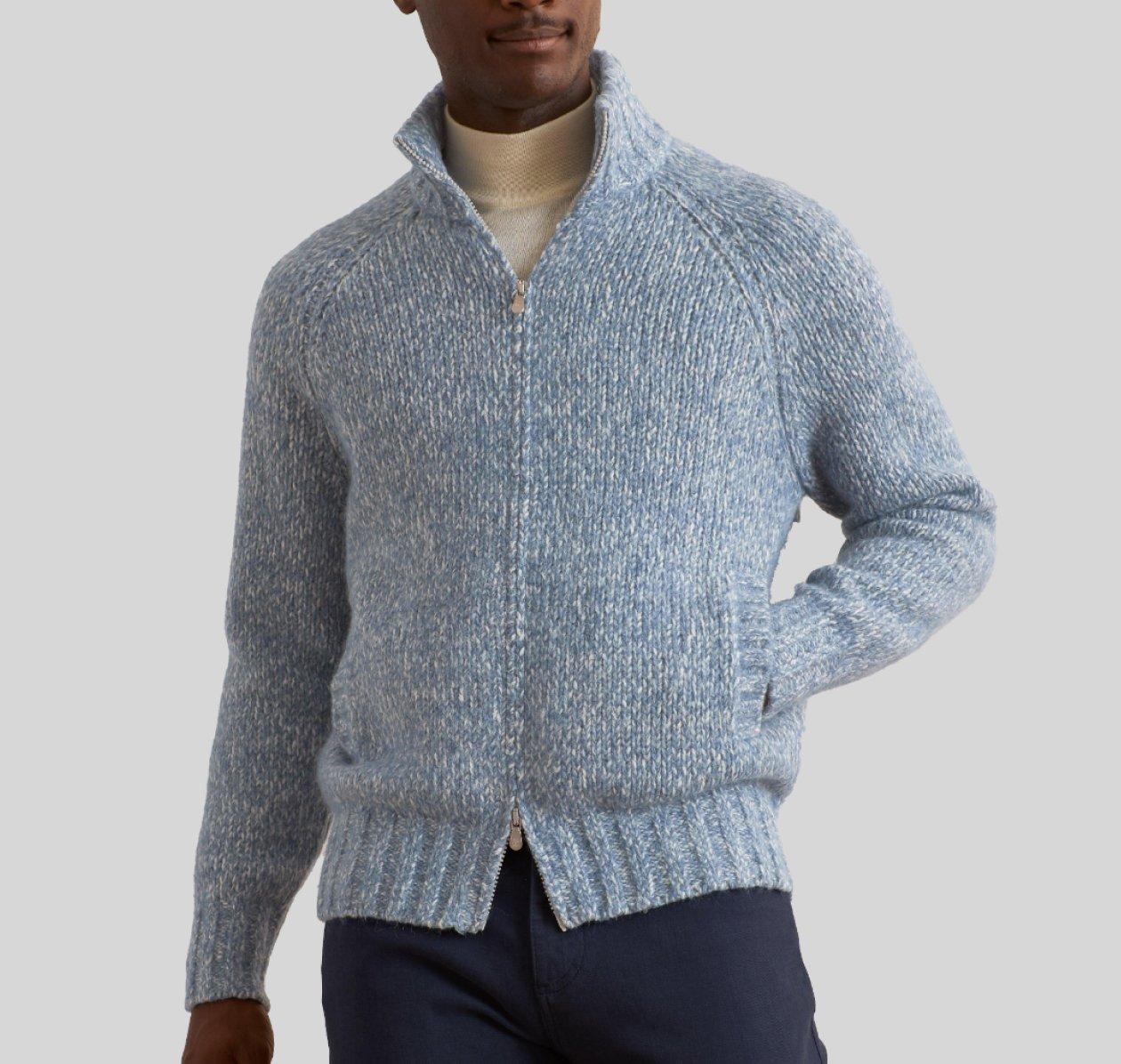 Male model wearing a light blue Brunello Cucinelli full-zip knit sweater styled with an ecru turtleneck and navy pants