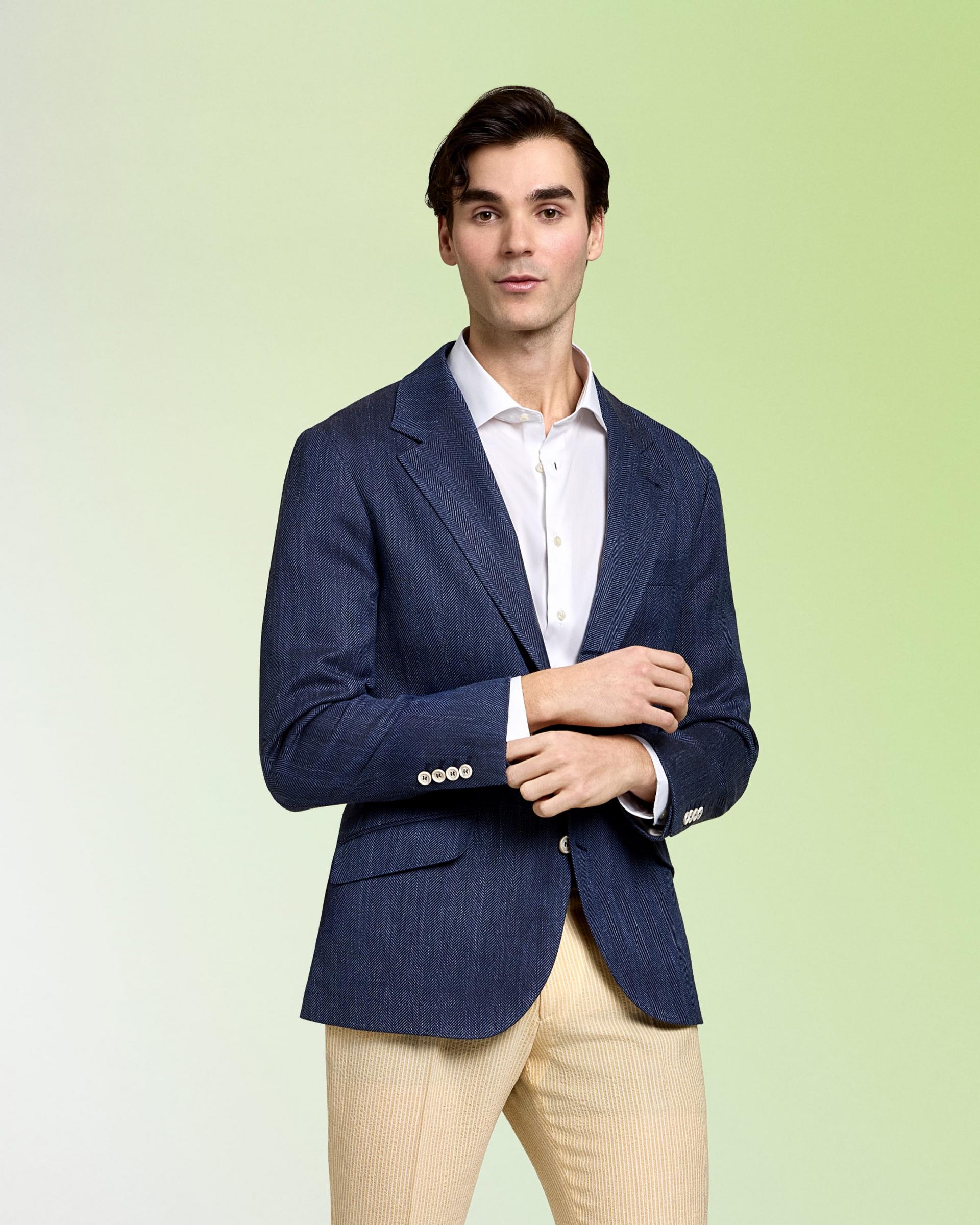 A model wearing a navy blazer and white dress shirt with khaki pants