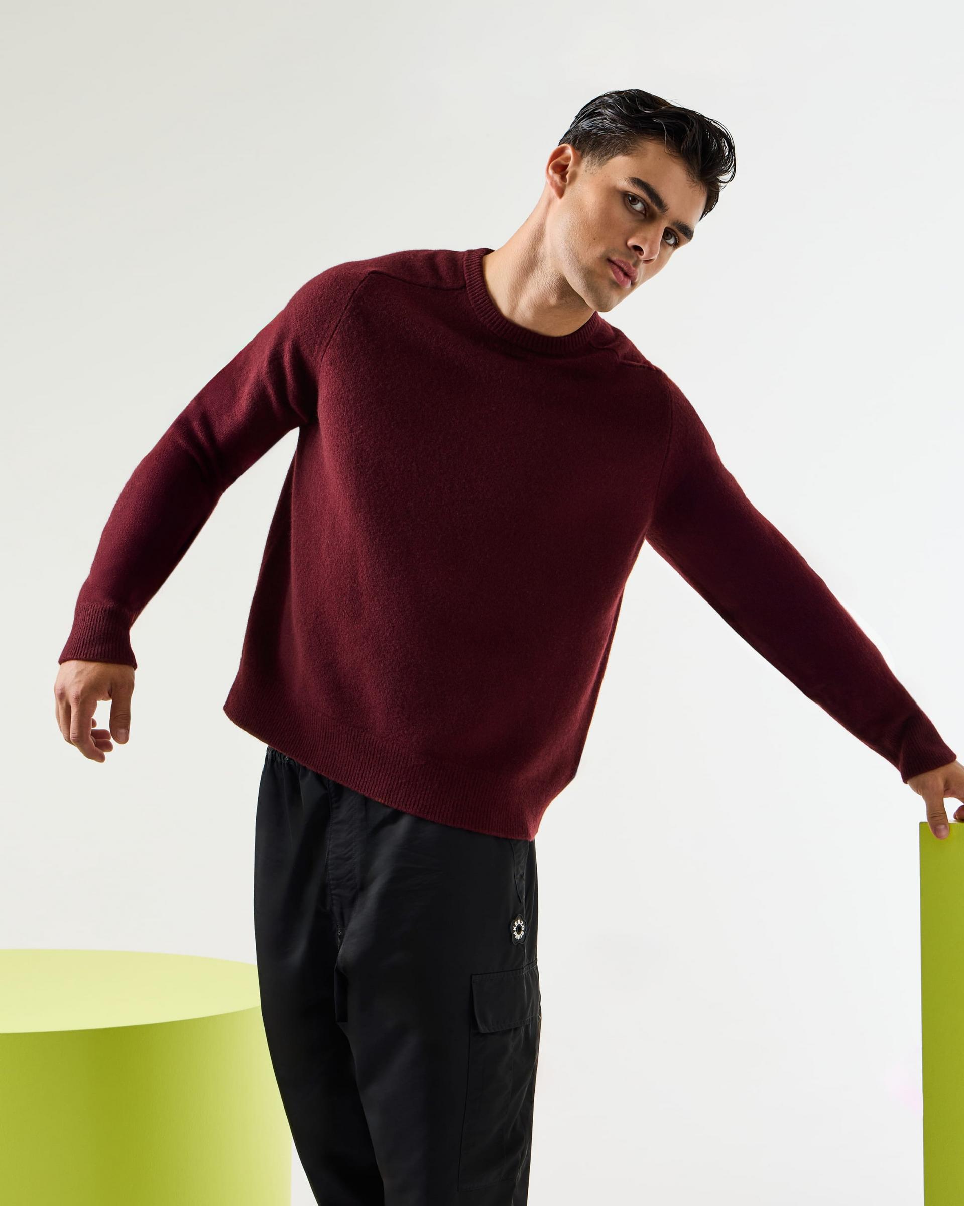 A model wearing a burgundy sweater