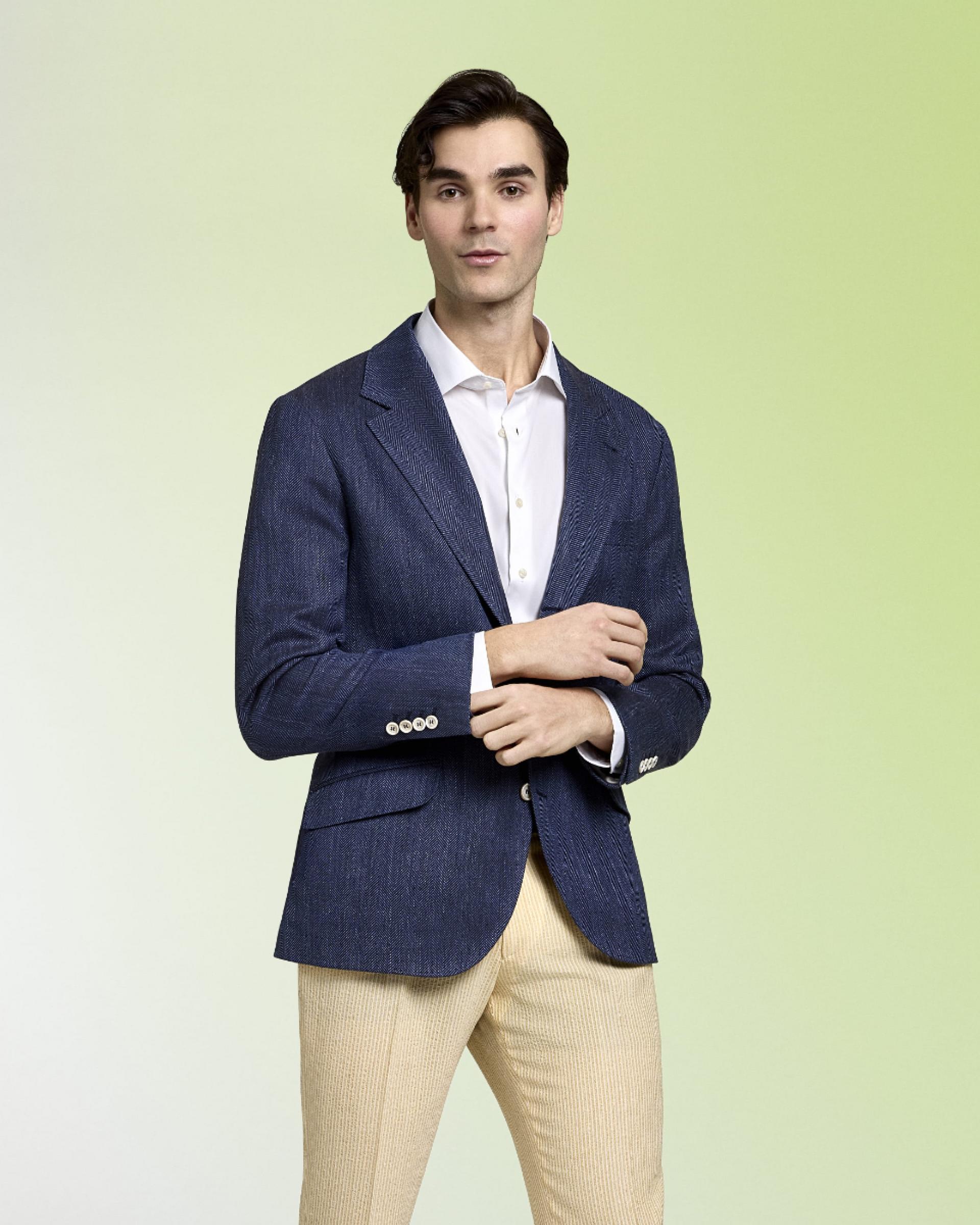 A man wearing a Navy Blue Sport Jacket with white shirt and beige pant