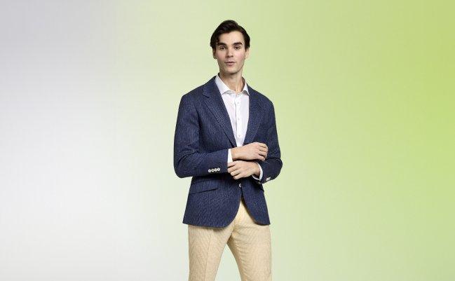 Un homme portant un veston sport bleu marine avec une chemise blanche et un pantalon beige