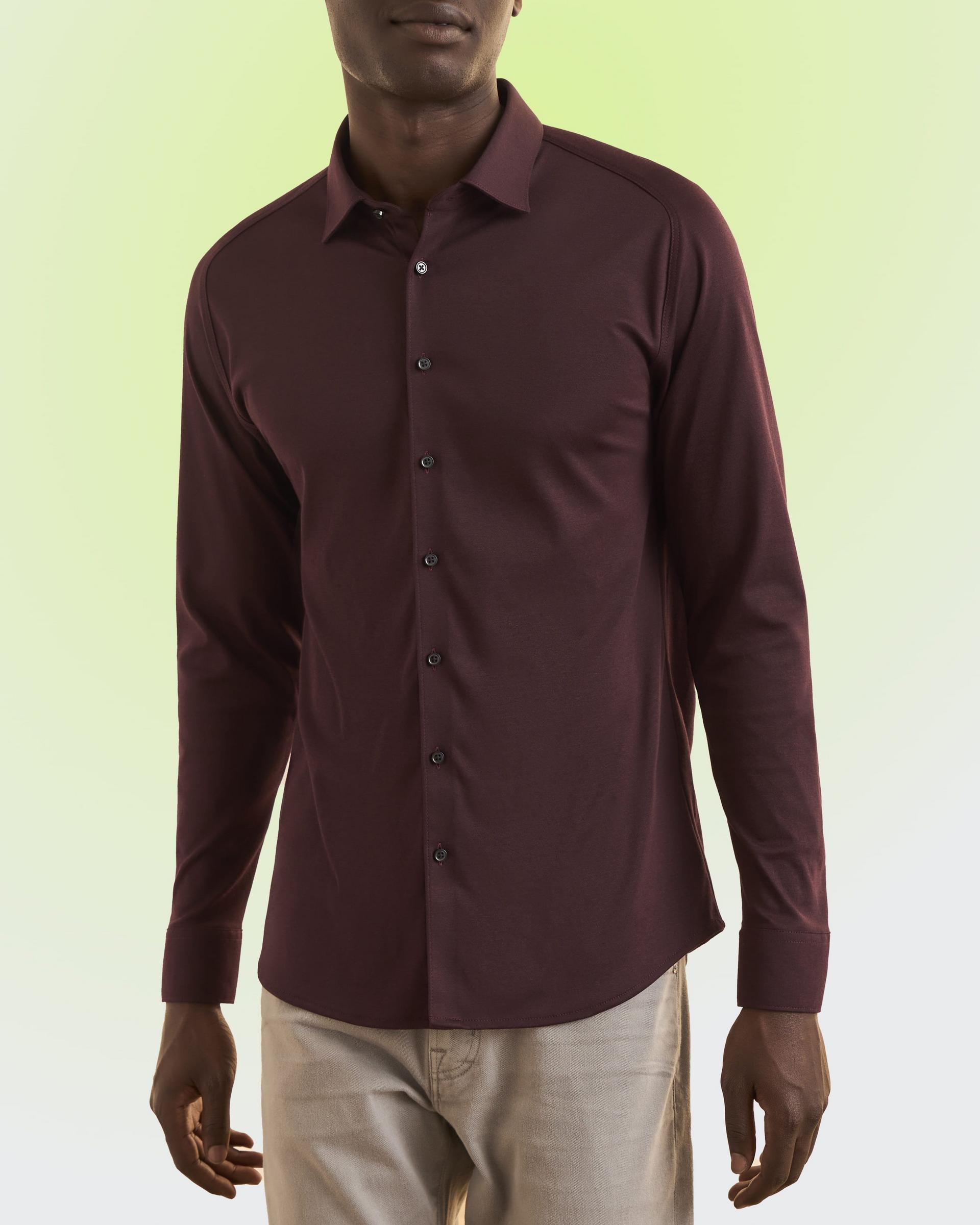 A man wearing a dark brown shirt and off-white pants