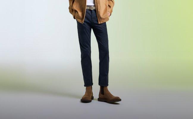 A male model wearing dark blue Paige jeans