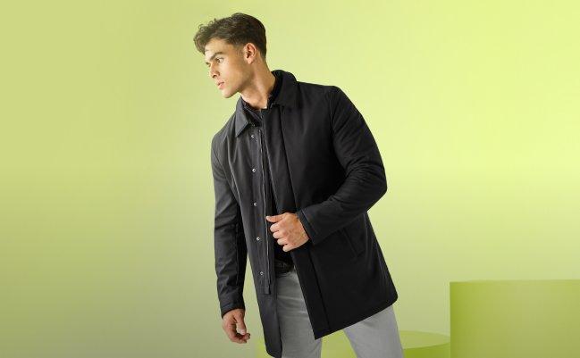A model wearing a black lightweight jacket paired with light pants
