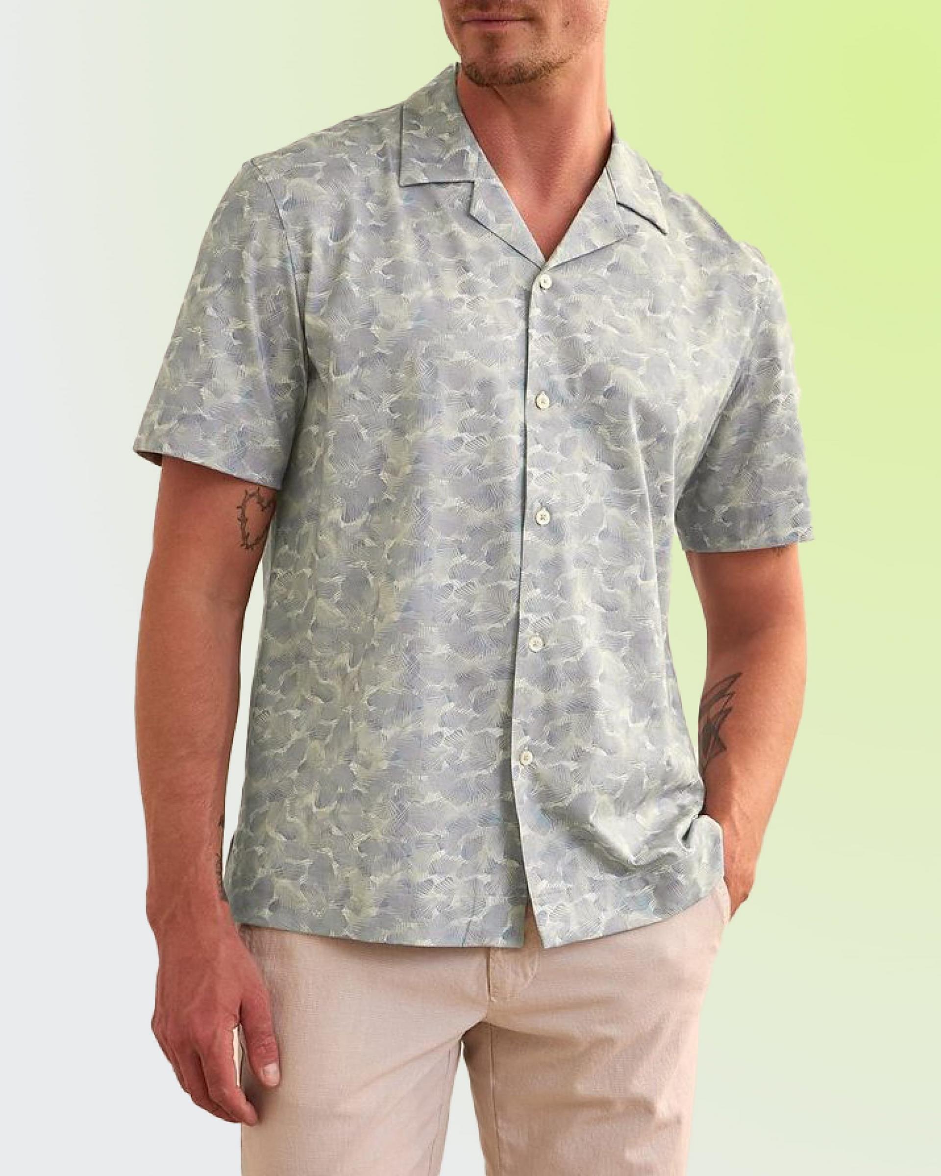 A male model wearing an olive green t-shirt styled with grey pants