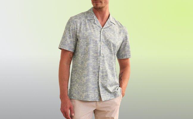 A male model wearing an olive green t-shirt styled with grey pants