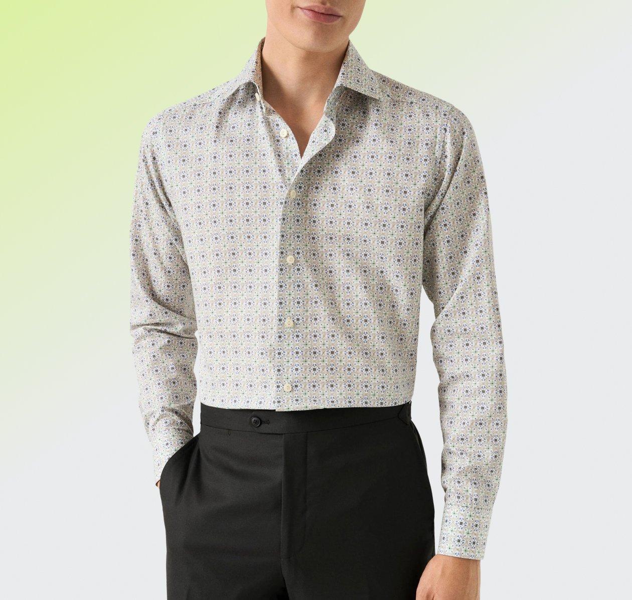 Un homme portant une chemise habillée à coupe contemporaine au motif discret de couleur pâle, assortie à un pantalon noir