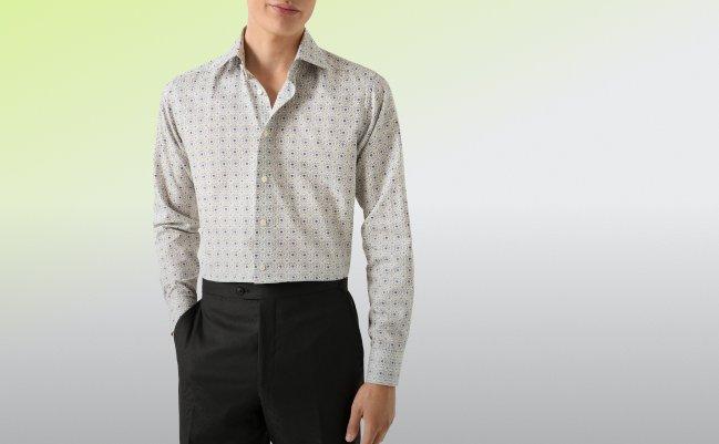 Un homme portant une chemise habillée à coupe contemporaine au motif discret de couleur pâle, assortie à un pantalon noir