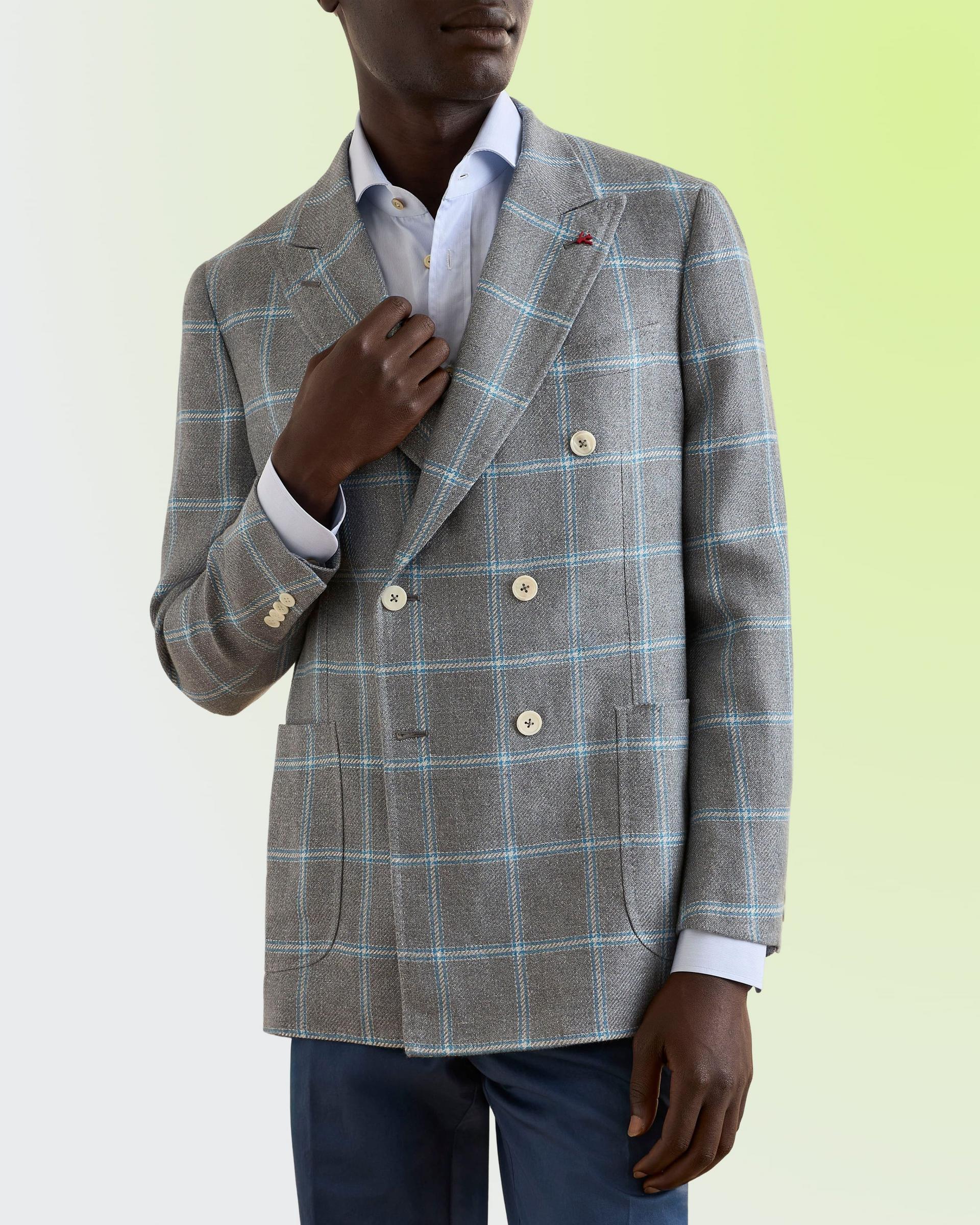 A model wearing a Sport Coat in a light grey wool blend with blue and white checks, paired with a white dress shirt and dark trousers