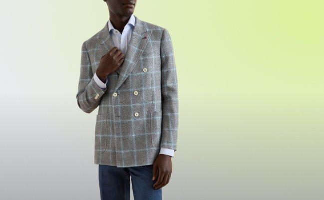 Un mannequin portant un veston sport en mélange de laine gris pâle à carreaux bleus et blancs, agencé avec une chemise habillée blanche et un pantalon foncé