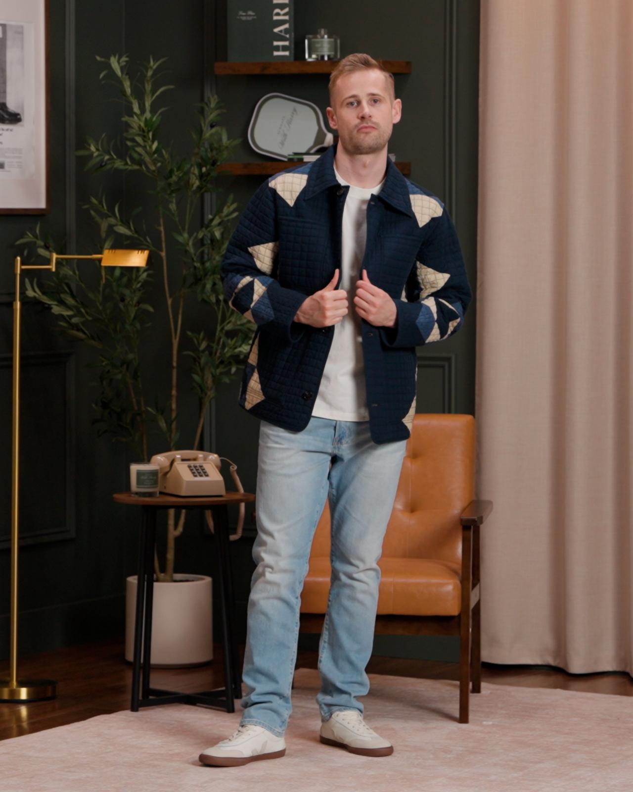 Mannequin portant une veste matelassée bleu marine avec des empiècements à motifs beiges, un t-shirt blanc uni, un jean bleu clair et des baskets blanches