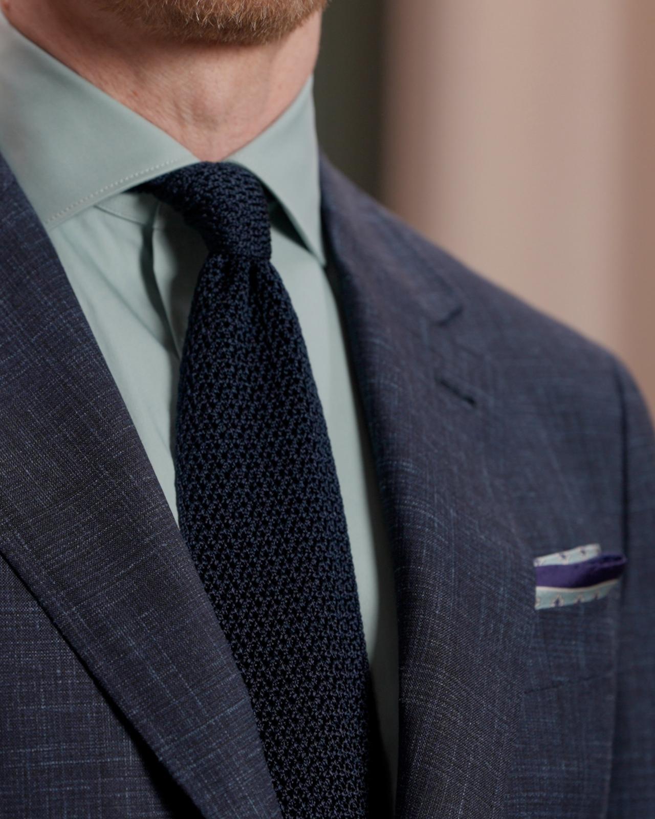 Un homme portant une cravate noire en laine avec une chemise mauve poudré