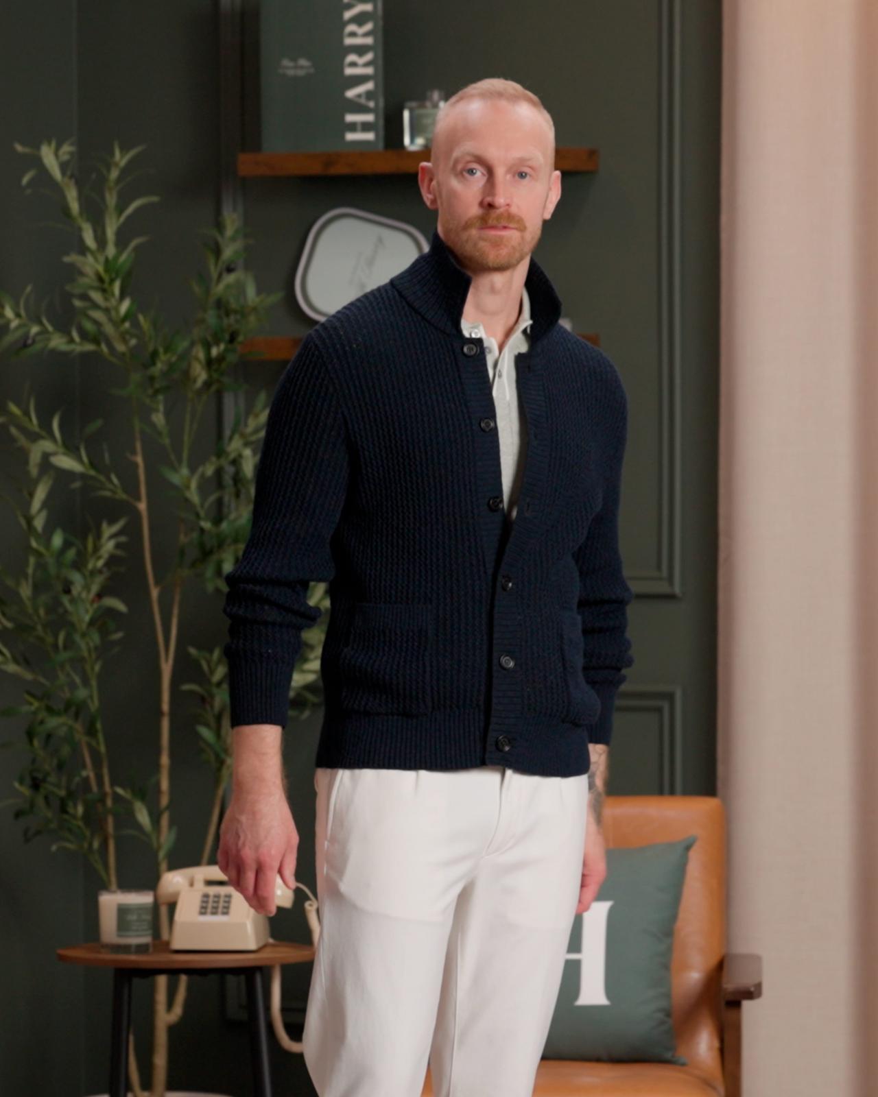 Mannequin de mode portant un cardigan bleu marine boutonné par-dessus une chemise blanche à col, assorti à un pantalon blanc
