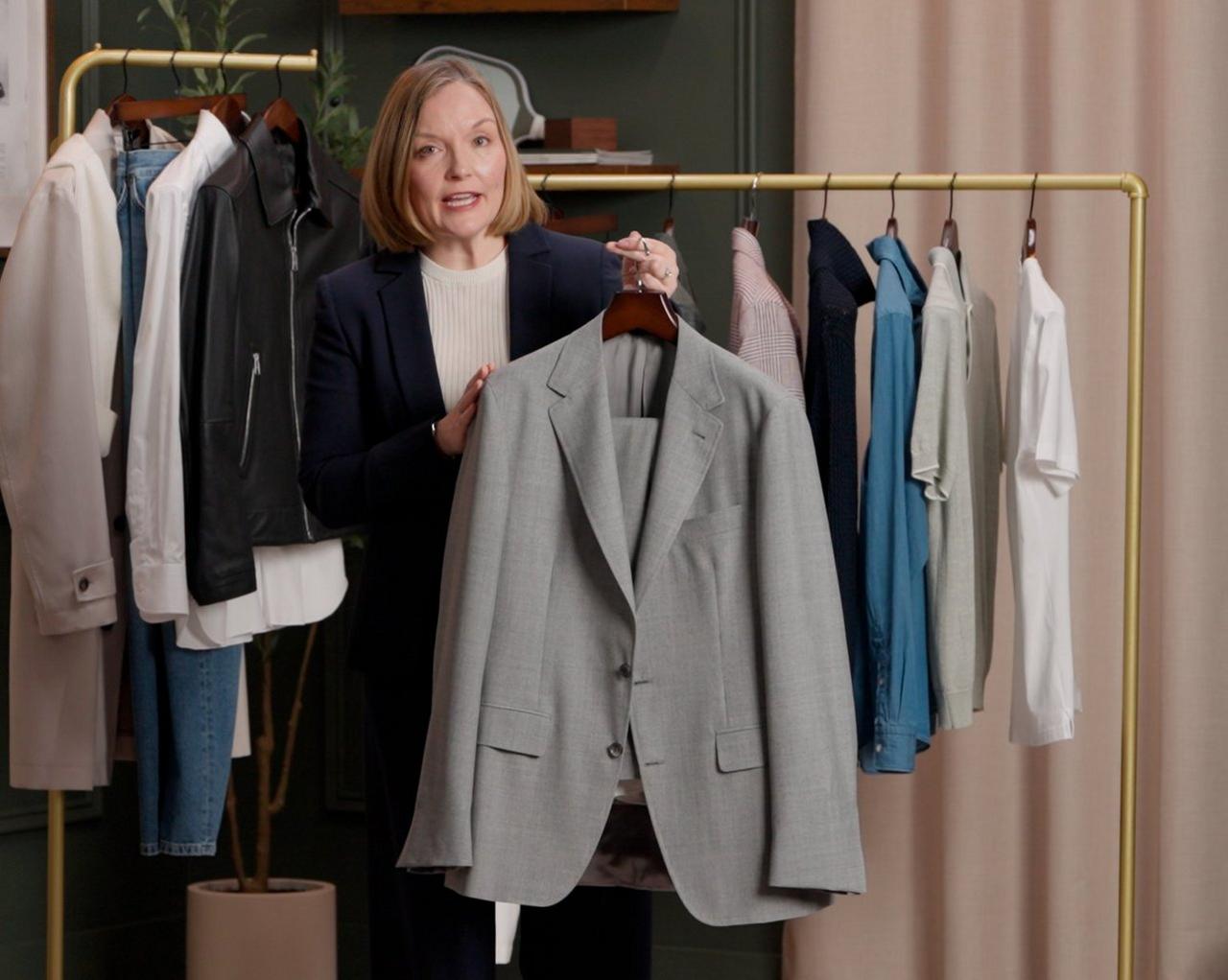 An associate holding a light gray suit jacket on a hanger