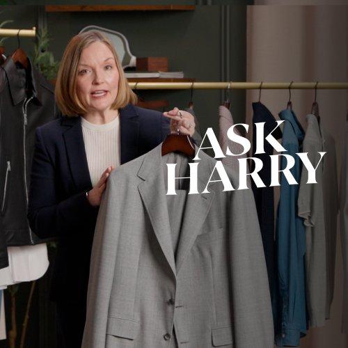 Un conseiller tenant une veste de costume gris clair sur un cintre, avec un texte superposé indiquant « ASK HARRY –  COMMENT CRÉER UNE GARDE-ROBE CAPSULE POUR HOMMES »