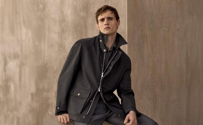 A model wearing a black water resistant Brunello Cucinelli jacket, styled with a knit polo, and black trousers