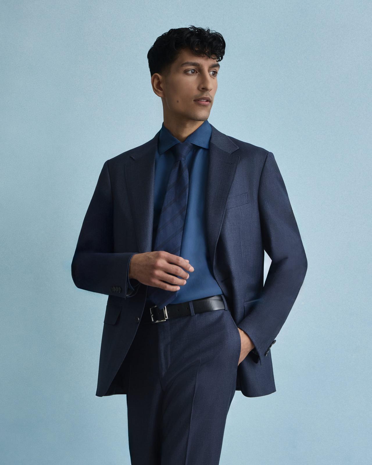 A model wearing a navy Canali tailored suit, navy tie, paired with a royal blue dress shirt