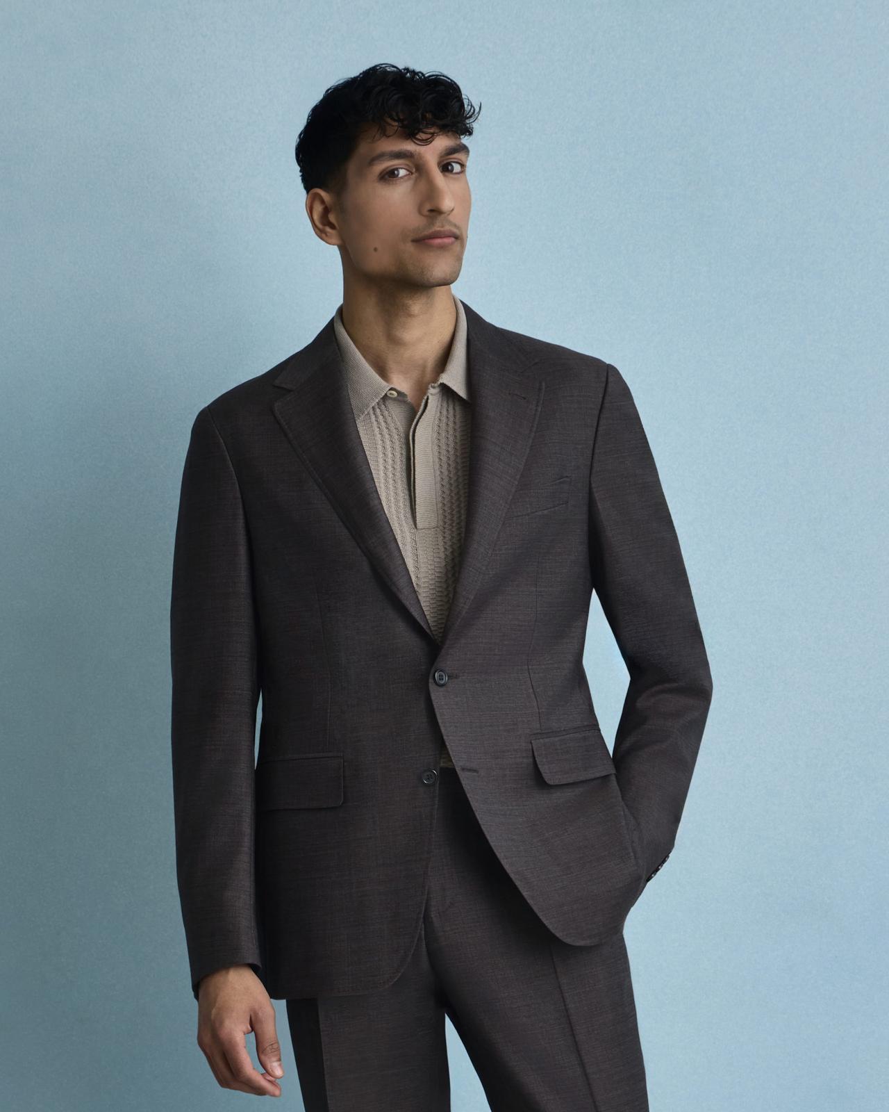 Mannequin homme portant un complet classique noir Canali, assorti à un polo en tricot brun clair