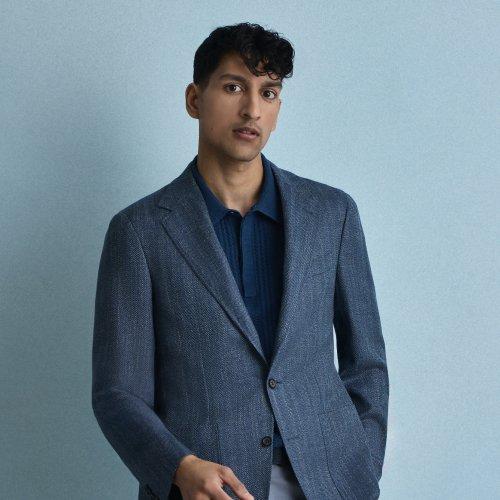 Un homme portant une veste sport bleue Canali avec un polo bleu foncé