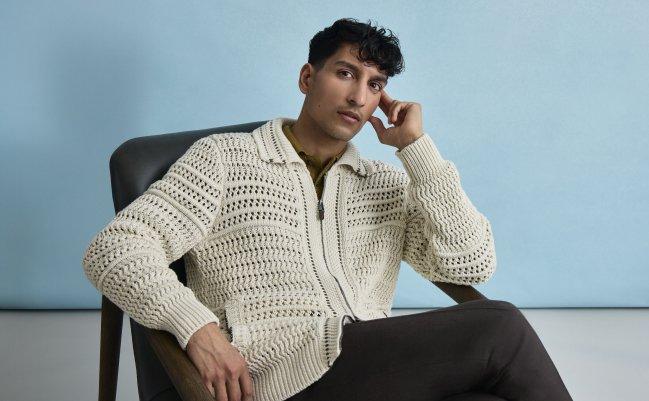 A man wearing Canali's off-white zipped sweater with black pant