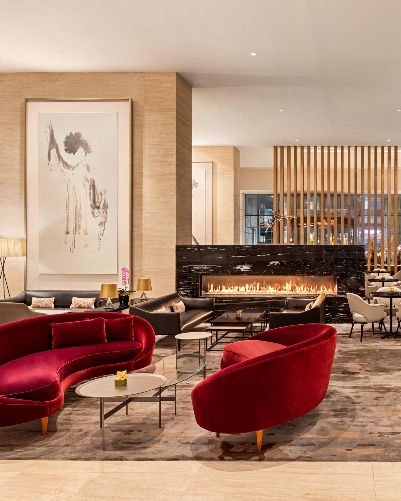 Lobby Lounge at the Shangri-La Hotel Toronto, featuring plush red velvet seating, a sleek black marble fireplace, and warm ambient lighting