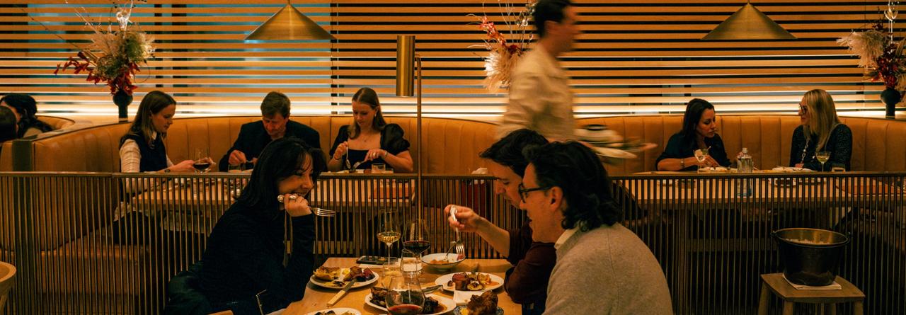  Diners enjoying a meal in a warmly lit restaurant with wooden paneling and modern decor