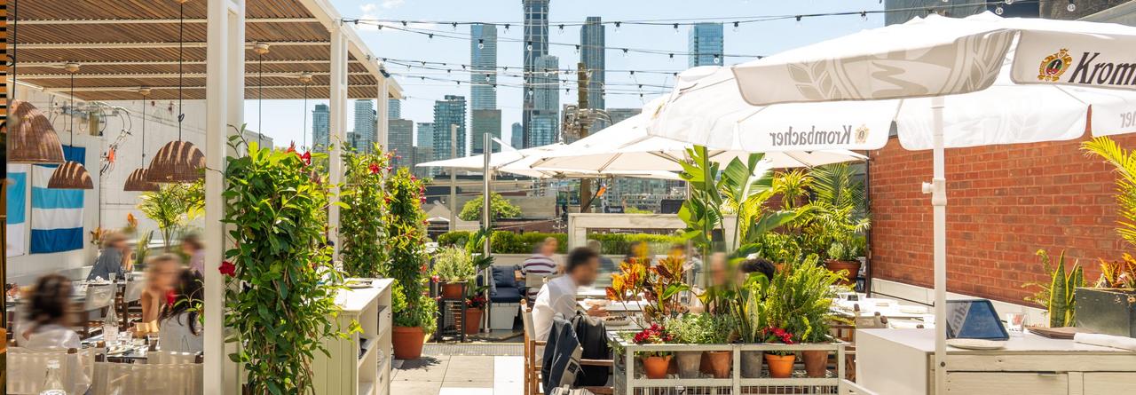 A lively rooftop dining scene with people enjoying meals under string lights