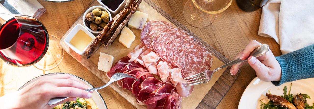 An Italian charcuterie board featuring cured meats, cheeses, olives, and breads