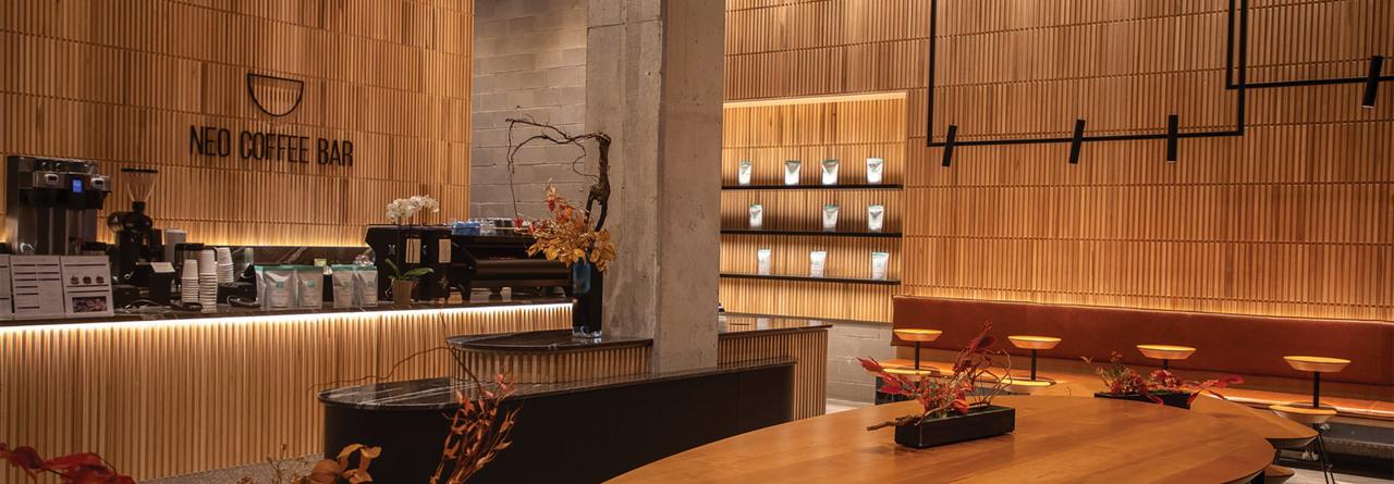 Neo Coffee Bar, featuring warm wood paneling, minimalist seating, and a sleek counter with coffee-making equipment