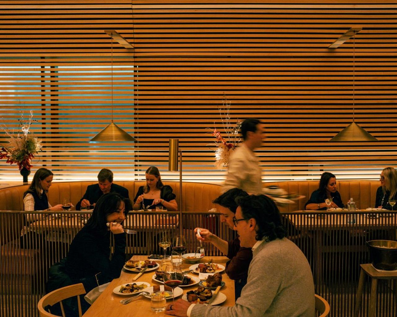  Diners enjoying a meal in a warmly lit restaurant with wooden paneling and modern decor