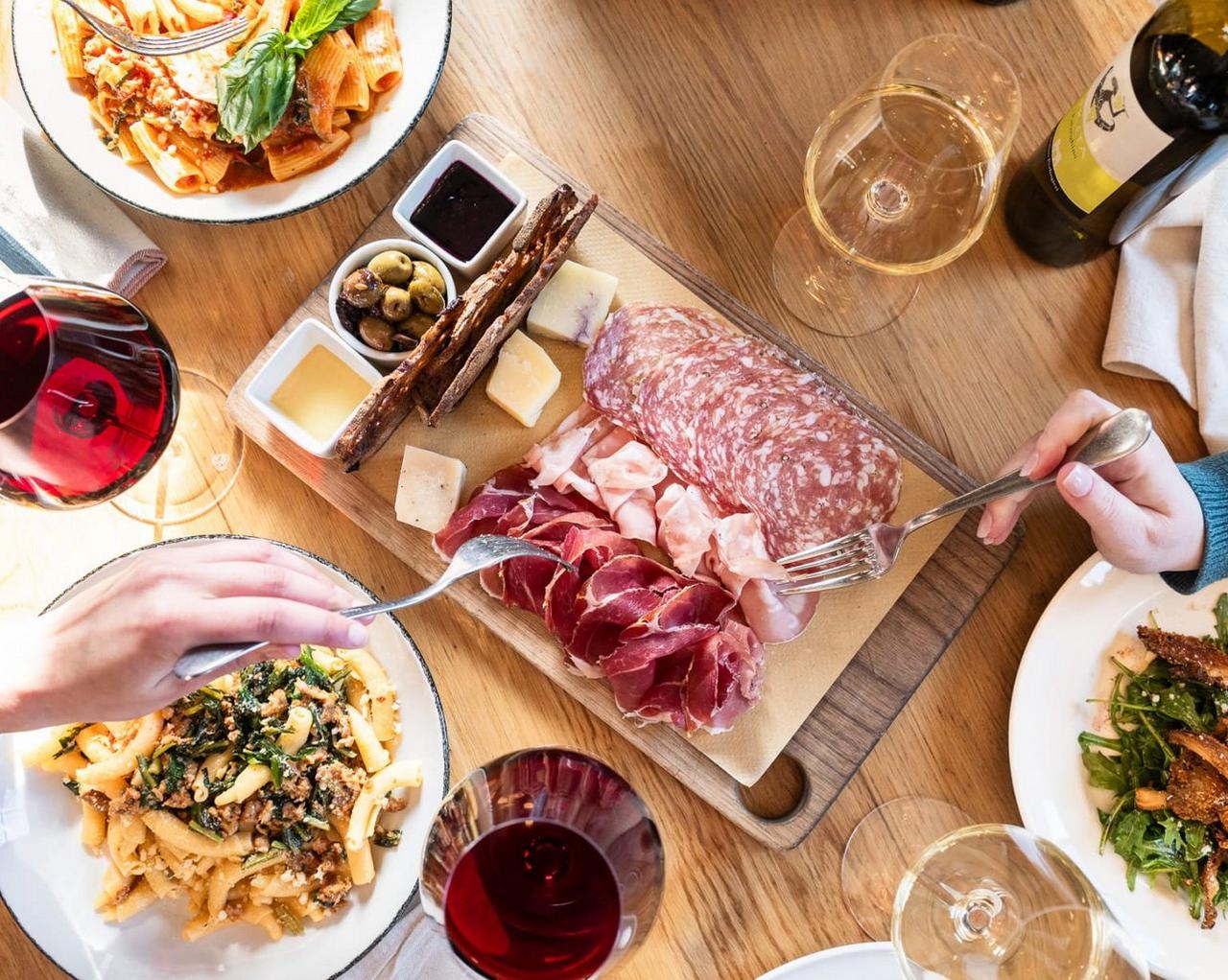 An Italian charcuterie board featuring cured meats, cheeses, olives, and breads