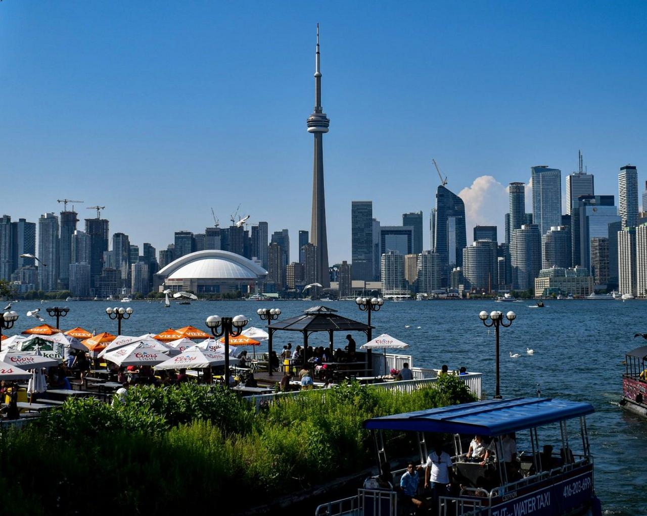 La silhouette de Toronto vue depuis l’autre côté de l’eau, avec l’emblématique tour CN qui s’élève au-dessus des gratte-ciel modernes de la ville
