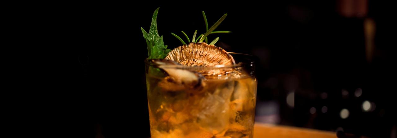 Moutai African Sunrise Cocktail served in a rocks glass, garnished with a dried fruit slice and fresh herbs