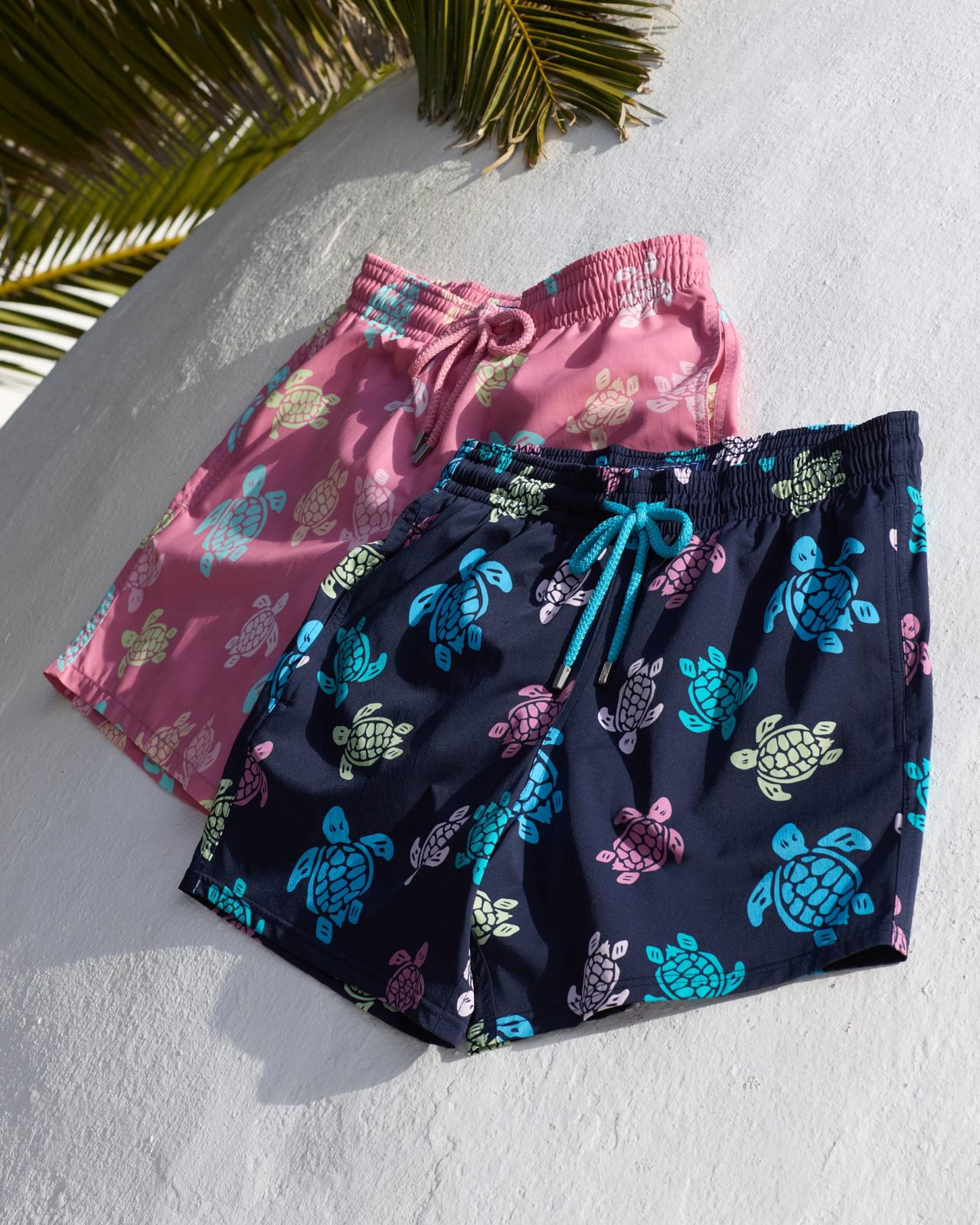 Two pairs of swim shorts with colorful sea turtle patterns