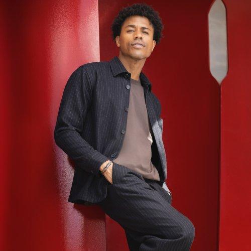 Man in open button-down shirt and T-shirt against red background