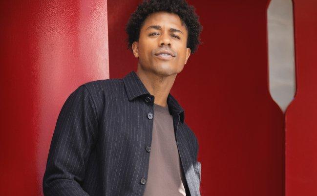 Homme portant une chemise boutonnée ouverte et un t-shirt sur un fond rouge