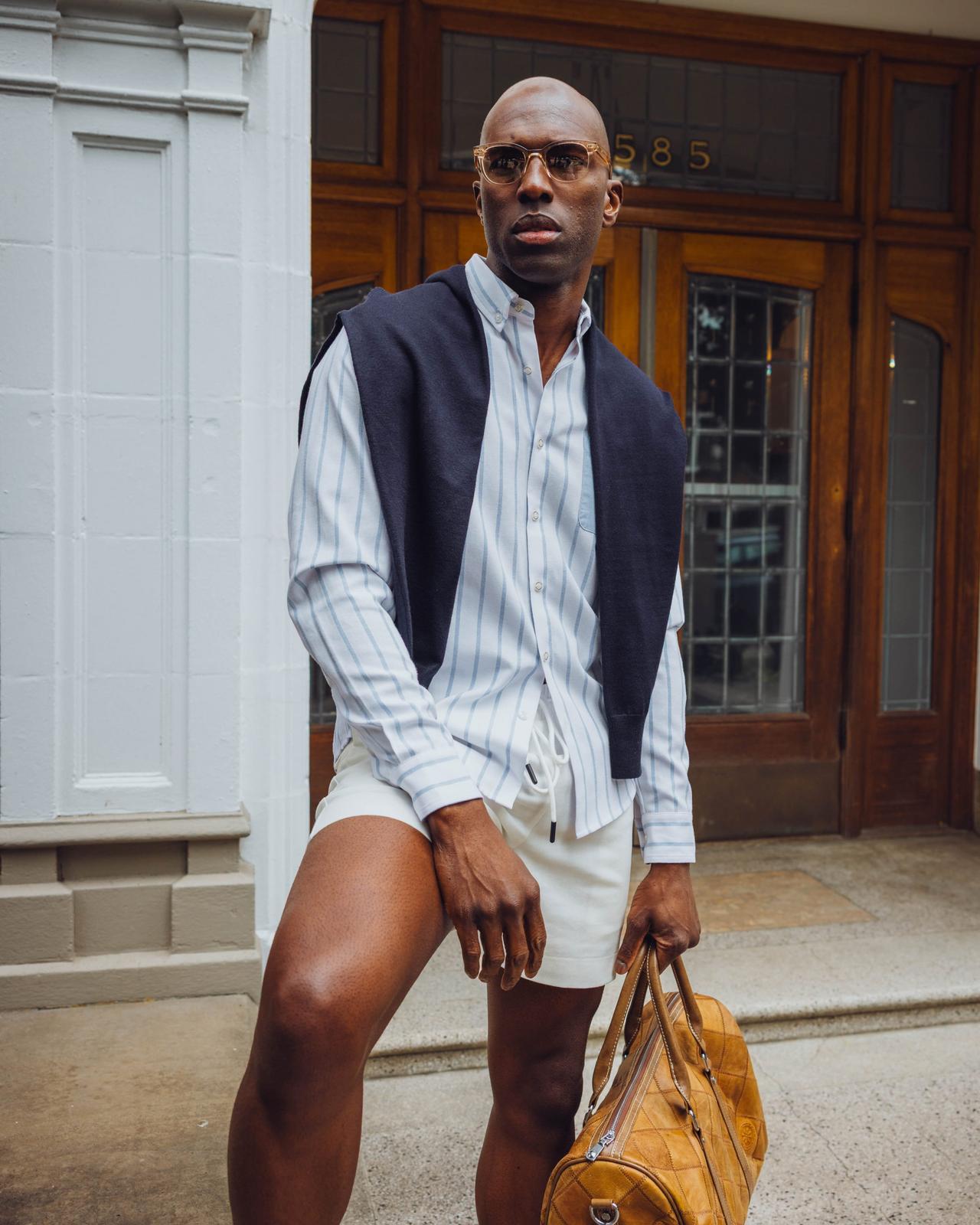 A man wearing white and blue striped shirt with off-white shorts