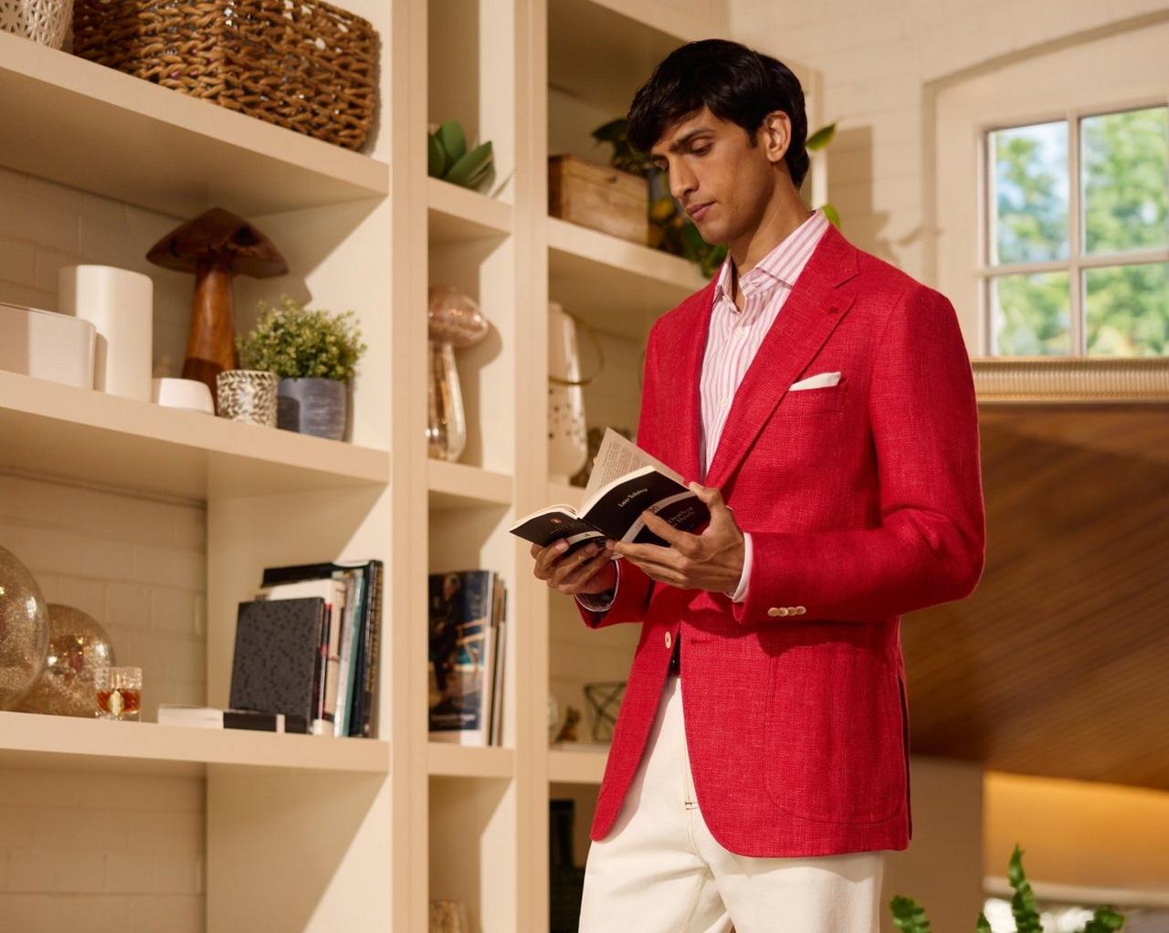 Un homme portant un veston sport rouge avec une chemise blanche et rose, et une pochette blanc cassé.