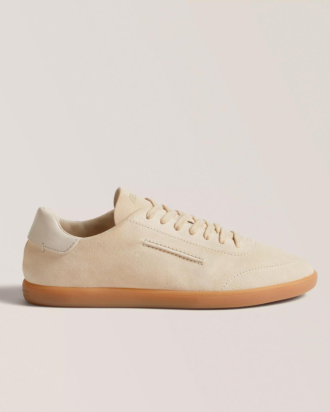 Beige suede sneakers with a low-top silhouette, light leather laces, and a gum sole
