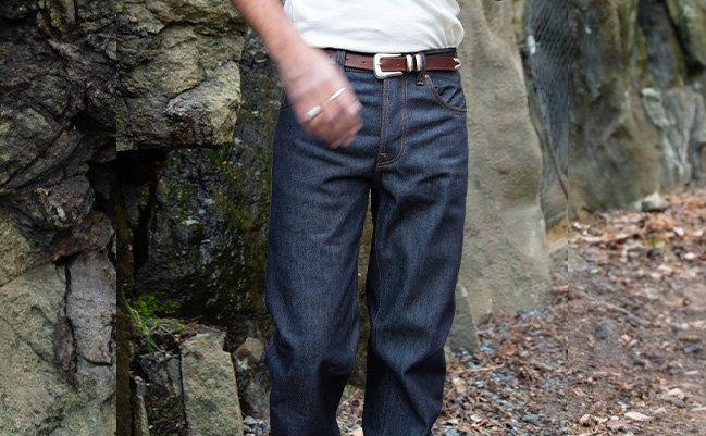 A model wearing Nudie jeans styled with a leather belt and a white t-shirt